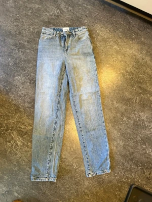 Blå raka jeans från Abrand Jeans - Säljer ett par klassiska blå jeans från Abrand Jeans med rak passform och hög midja. Jeansen har fem fickor, bälteshällor och stängs med dragkedja och knapp. Tillverkade i slitstark denim som ger en tidlös look.