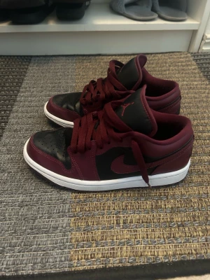 Nike Air Jordan 1 Low. vinröda  - Säljer ett par Nike Air Jordan 1 Low i svart och vinrött. Använda ett fåtal gånger men fortfarande i bra skick. 