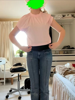 Ljusrosa croppad t-shirt soc - Säljer en ljusrosa croppad t-shirt från soc med korta ärmar och rund hals. Tillverkad i mjuk bomull och har en liten soc-logga nere vid fållen. Perfekt för träning eller chill dagar.