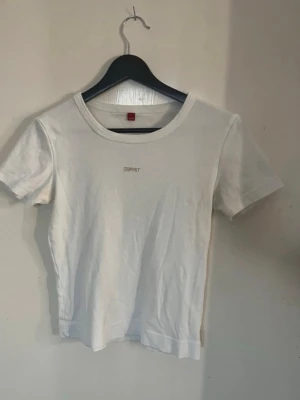 Vit t-shirt från Esprit - Klassisk vit t-shirt från Esprit med diskret logga broderad framtill. Modellen har rund halsringning och korta ärmar. Tillverkad i mjuk bomull för en bekväm känsla och passar perfekt till alla dina outfits. Säljer en likadan i svart, kolla in fler artiklar för bundle rabatt! 