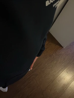 Svart hoodie från Björn Borg - En svart sweatshirt från Björn Borg med vit logga tryckt på bröstet. Klassisk rund hals och långa ärmar. Perfekt för en avslappnad och sportig stil.