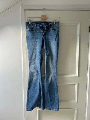 Blå bootcut jeans från Vero Moda - Säljer ett par ljusblå bootcut jeans från Vero Moda. Jeansen har klassisk femficksmodell, låg midja och utsvängda ben. 