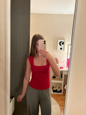 Röd ärmlös linnetopp - Snygg röd linnetopp med fyrkantig ringning och tight passform. Toppen är ärmlös och har en enkel, stilren design som passar perfekt till jeans eller kjol. Perfekt för dig som gillar färg och vill ha en basic topp i garderoben. Lappen finns kvar. Priset kan diskuteras ❣️