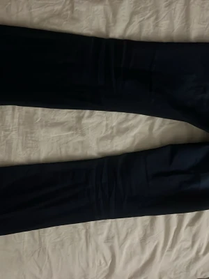 Mörkblå jeans med kontrastsömmar - Snygga mörkblå jeans med raka ben och tydliga vita kontrastsömmar. Jeansen har två bakfickor med lock och silverfärgade knappar. Klassisk femficksmodell i stretchigt denimtyg som passar perfekt till en avslappnad stil.