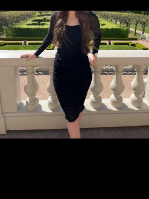 Svart långärmad meshklänning - Säljer en svart, figurnära klänning med lång ärm och meshdetaljer. Klänningen har en kroppsnära passform och slutar strax ovanför knäna. Perfekt för dig som gillar en stilren och trendig look.