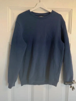 Mörkblå basic sweatshirt - En enkel och stilren mörkblå sweatshirt med rund halsringning och långa ärmar. Tröjan har en avslappnad passform och ribbade muddar vid ärmslut och nederkant. Perfekt att matcha med jeans eller kjol för en casual look.