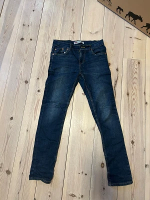 Mörkblå Levi's jeans - Snygga mörkblå skinny jeans från Levi's med klassiska fem fickor och gul söm. Jeansen har en smal passform och är tillverkade i denim med en liten stretch för extra komfort. Perfekta till en avslappnad streetstyle-look.