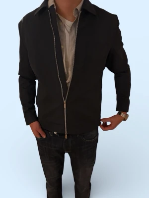 Svart/grå overshirt med dragkedja - Stilren svart overshirt med hel dragkedja framtill och klassisk krage. Jackan har lång ärm och en enkel, clean look som passar till det mesta. Tillverkad i ett mjukt material som känns bekvämt och lätt att bära.