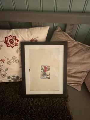 Charizard V Pokémonkort i ram - Säljer ett Charizard V Pokémonkort som är inramat i en svart ram med vit passepartout. Kortet har en holografisk yta med motiv av Charizard och detaljer i rött, svart och gult. Perfekt för samlare eller Pokémonfans som vill ha något unikt på väggen. Pris på andra ställen kan bara mellan 3-5 tusen😅