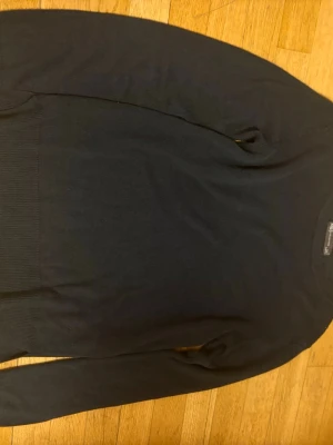 Mörkblå stickad tröja - En enkel och stilren mörkblå stickad tröja med rund halsringning och långa ärmar. Tröjan har ribbade muddar vid ärmslut och nederkant, vilket ger en klassisk look. Perfekt att matcha med jeans eller kjol för en clean outfit. Storlek xs. Priset går att diskutera. Använd fåtal gånger. Frakt ingår ej!