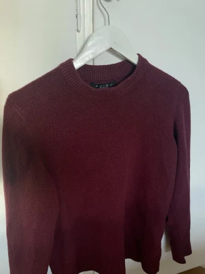 Vinröd stickad tröja från Amisu - Mysig vinröd stickad tröja från Amisu med rund halsringning och ribbade muddar vid ärmslut och nederkant. Perfekt för kyliga dagar och enkel att matcha med jeans eller kjol. 