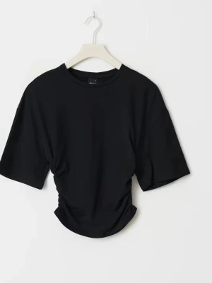 Svart croppad t-shirt med snörning - Stilren svart t-shirt med croppad passform och snygg snörning i sidorna. T-shirten har rund halsringning och korta ärmar, perfekt för en trendig vardagslook.