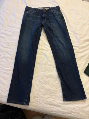 Mörkblå raka jeans från Lee - Säljer ett par klassiska mörkblå jeans från Lee med rak passform. Längden på byxorna är 34, Innerbenslängden är 84/85cm. Storlek på jeansen är L. Tillverkade i slitstark denim som passar perfekt till en avslappnad stil. 