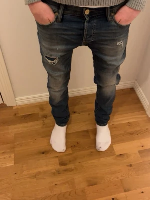 Blåa skinny jeans med slitningar - Säljer ett par blåa baggy jeans med tydliga slitningar och hål på ena låret. Jeansen har låg gren, klassisk femficksmodell och en avslappnad passform. Perfekta för en streetwear-look och riktigt sköna att bära. Skriv för mer info 
