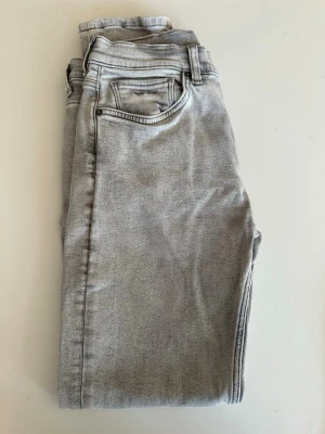 Grå slim fit jeans från gant - Snygga grå slim fit jeans från gant med klassisk femficksmodell och normal midja. Jeansen har en stilren look och raka ben, perfekta till en avslappnad outfit. Materialet känns mjukt och stretchigt för extra komfort.