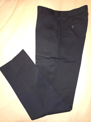 Marinblå kostymbyxor, regulsr - Kostymbyxor – Marinblå (W32/L32, okänt märke) Mörkblå kostymbyxor, okänt märke. Storlek: W32 / L32 Skick: Bra begagnat skick. Passform: Regular.