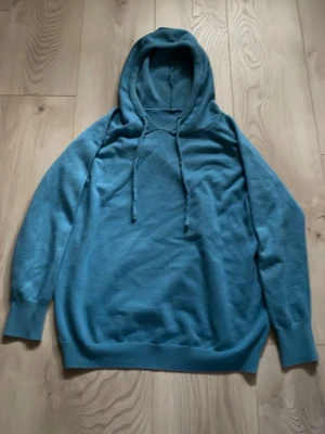 Blå hoodie  - Snygg blå hoodie med huva och matchande dragsko. Hoodien har en avslappnad passform, långa ärmar och ribbade muddar vid ärmslut och nederkant. Perfekt för en chill och casual stil. Materialet känns mjukt och bekvämt.