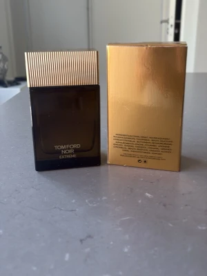 Tom Ford Noir Extreme Eau de Parfum - Tom Ford Noir Extreme Eau de Parfum i en elegant mörkbrun glasflaska med guldfärgat lock och matchande guldig kartong. Flaskan har en stilren, fyrkantig form och utstrålar lyxig känsla. Perfekt för dig som gillar exklusiva dofter och snygg design. Nästan helt oanvänd också.