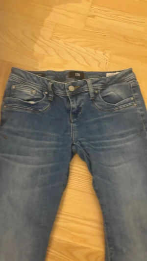 Blå bootcut jeans från LTB - Säljer ett par blå bootcut jeans från LTB med klassisk femficksmodell och snygga slitningar på låren. Jeansen har normal midja och dragkedja med knapp. Perfekta för dig som gillar en avslappnad men ändå trendig look.