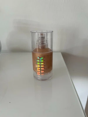 MILK glow primer - Oanvänd Milk glow primer i en genomskinlig plastflaska med pump. Färgen är varm beige med gyllene underton och flaskan har holografiska detaljer på framsidan. Enkel att dosera tack vare pumpen och perfekt för en jämn bas.