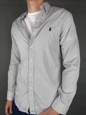 Ralph Lauren skjorta - Ralph Lauren Skjorta Märke: Polo Ralph Lauren Storlek: M Passform: Slimfit Färg: Vit/svart randig Skick: Mycket bra Beskrivning: utan defekter. Modellen på bilden: 183 cm / 75 kg