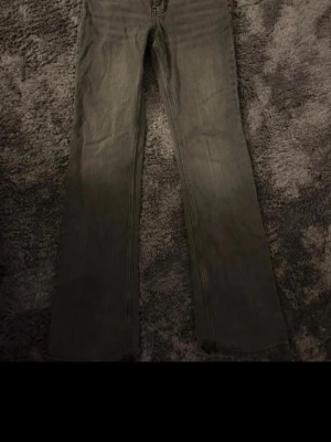 Grå bootcut jeans - Snygga grå jeans med bootcut passform och klassiska fem fickor. Jeansen har raka ben och är tillverkade i ett mjukt denimtyg som ger en avslappnad look. Perfekta för dig som gillar en tidlös och enkel stil.