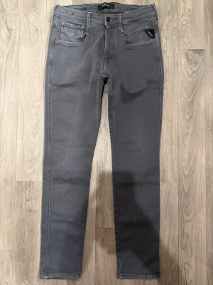Replay Anbass Hyperflex Jeans Grå W31 - Slim Fit - Replay Anbass Hyperflex grå jeans i stretchig Hyperflex denim med slim fit passform som sitter snyggt och bekvämt och funkar till allt, storlek W31/L okänd (innerlapp avklippt), midja 38 cm, ytterbenslängd 101 cm, benöppning 15 cm, modellen är 185cm & väger 65kg, i fint skick.