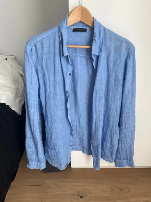 Ljusblå linneskjorta Made in Italy - Snygg ljusblå skjorta i linne från Made in Italy. Skjortan har klassisk krage, knappar framtill och långa ärmar. Perfekt för en avslappnad och stilren look.