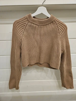 Beige cropped stickad tröja Zara - Snygg beige cropped stickad tröja från Zara med grov ribbstickning och rund hals. Tröjan har långa ärmar och en avslappnad passform, perfekt att styla med höga jeans eller kjol. Passar mig som normalt har strl M.