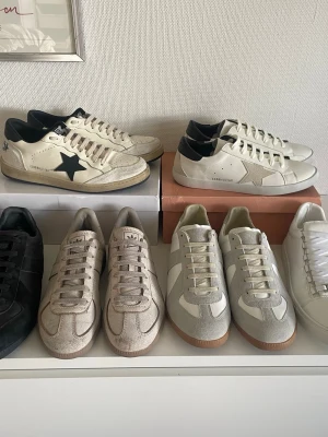 👟 DESIGNER SNEAKERS – KOM MED BUD! 👟 - 📋 Information om skorna: 1 Maison Margiela Replica GATs (Beige/Vit)  Storlek: 40  Skick: Bra begagnat skick, klassisk modell. 2 Balenciaga Arena (Vita)  Storlek: 40  Skick: Stilrena helvita lädersneakers i fint skick. 3 Adidas Replica/GATs (Beige)  Storlek: 40  Skick: Cool texturerad/cracked läderfinish. 4 Maison Margiela Replica GATs (Svarta)  Storlek: 44  Skick: Snygg kombo av svart läder och mocka. 5 Golden Goose Ballstar  Storlek: 43   6 Golden goose superstar storlek 42