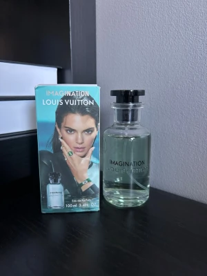 Louis vuitton Imagination - Louis Vuitton Imagination parfym i en elegant glasflaska med svart lock och grönblå vätska. Flaskan har en stilren form och tydlig logga. Förpackningen har tropiskt motiv med palmer och havsutsikt. Volymen är 100 ml. Kvitto finns inte men batchkod finns 