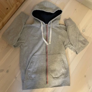 ZIP-HOODIE | PIER ONE. - Säljer en grå hoodie med dragkedja och vit snörning i huvan. Hoodien har fickor framtill och en randig detalj längs dragkedjan. Insidan av huvan är mörkblå. Perfekt för en avslappnad och sportig stil.