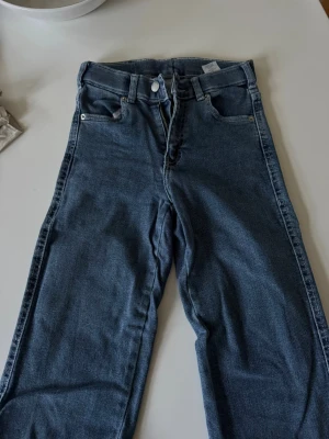 Blå raka jeans från DrDenim - Snygga blå jeans från DrDenim med raka ben och klassisk femficksmodell. Jeansen har hög midja och är tillverkade i ett mjukt denimtyg. Perfekta för en avslappnad och trendig stil.