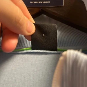 Ljusblå ziptröja från BOSS - Säljer en ljusblå ziptröja från BOSS med vit dragkedja och diskret BOSS-logga i vitt på bröstet. Tröjan har ståkrage och två fickor framtill med dragkedja. Perfekt för en clean och sportig stil.