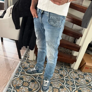 Replay anbass - Säljer ett par ljusblå slim fit jeans från replay med klassisk femficksmodell och snygga slitningar på låren. Jeansen har en diskret logga på bakfickan och är tillverkade i mjuk denim med stretch för extra komfort.