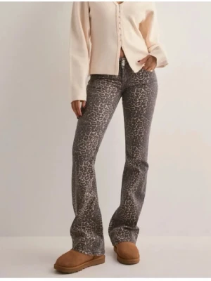 Leopardjeans Nelly - Säljer ett par snygga bootcut jeans med leopardmönster i grå och beige toner. Jeansen har normal midja, klassisk femficksmodell och stängs med knapp och dragkedja. Perfekta för dig som vill sticka ut lite extra! Storlek 38, knappt använda 