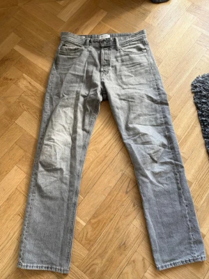 Grå raka jeans från Jack n jones - Snygga grå jeans från Weekday med rak passform och klassisk femficksdesign. Jeansen har normal midja och är tillverkade i ett mjukt denimtyg. Perfekta för en avslappnad och trendig look. 30/32