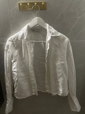 Vit linneskjorta från Zara - Säljer en luftig vit skjorta från Zara i linne. Skjortan har klassisk krage, långa ärmar och knappar framtill. 