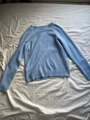 Ljusblå stickad tröja Vero Moda - Mysig ljusblå stickad tröja från Vero Moda med rund halsringning och ribbade muddar vid ärmslut och nederkant. Materialet känns mjukt och behagligt mot huden.