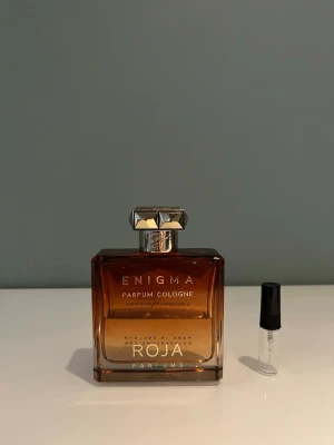 1 ml sample av Roja Enigma  - Ett sample av Roja Enigma 1 ml. Det är en maskulin doft som i öppningen får en Coca-Cola vibe och efter en stund blir det mer tobak och vanilj som träder fram vilket gör den väldigt bra på vintern. Våra samples är helt nya och gjorda i glas. Det är fritt fram att ställa frågor.