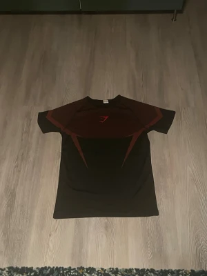 Gymshark onyx  - Snygg Gymshark onyx med röda detaljer och logga på bröstet., perfekt för gymmet eller löpning. Helt oanvänd,Storlek S,riktigt rare. 
