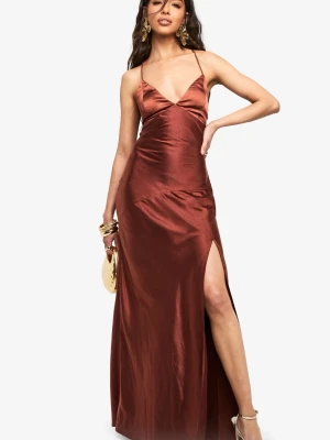 Brun långklänning med snörning - Elegant brun långklänning med smala axelband och v-ringad front. Klänningen har öppen rygg med snörningsdetaljer och en hög slits på sidan. Materialet har en lätt glans och faller snyggt. Perfekt för dig som vill sticka ut med en stilren look.
