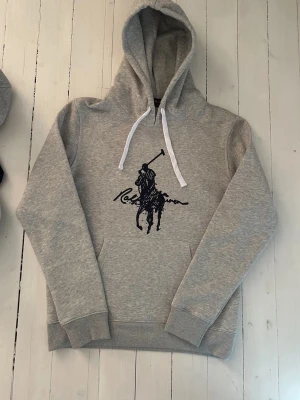 Ralph Lauren hoodie herr, storlek S - Hej! Säljer denna riktigt schyssta hoodie från Ralph Lauren. Den är i storlek M men sitter en storlek litet och passar därför som en S. Den är endast använd någon enstaka gång och är därmed i ett nyskick. Original lappar och påse finns kvar och medföljer naturligtvis vid köp. Jag fraktar alltid snabbt! Mvh