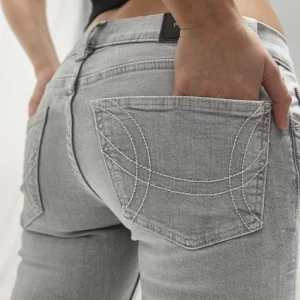 Ljusgrå bootcut jeans från Gina  - Säljer ett par ljusgrå jeans från Gina med bootcut passform och snygga vita kontrastsömmar på bakfickorna. Använda fåtal gånger🤍