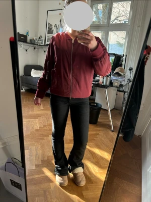 Vinröd bomberjacka med dragkedja - Snygg vinröd bomberjacka med silverfärgad dragkedja framtill och ribbade muddar vid ärmar och midja. Jackan har en klassisk bomberpassform och fickor på sidorna. Perfekt för dig som vill ha en stilren och trendig look. Har en del defekter. 