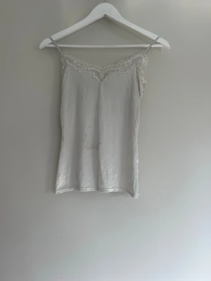 Vit spets linne ifrån Lindex - Säljer detta kräm vita spetslinne med tunna band ifrån Lindex i storlek S. Linnet har schysterbara band. Användt ett par gånger och har en liten fett fläck skulle jag säga på framsidan, men ingenting som syns jätte tydligt