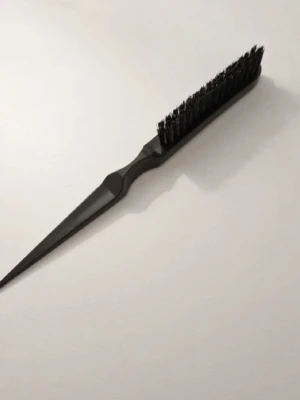 Svart tuperingsborste - Säljer en svart tuperingsborste med smal, spetsig plastända perfekt för att dela upp håret. Borsten har täta svarta borststrån och ett ergonomiskt handtag i plast. Perfekt för styling och att skapa volym.