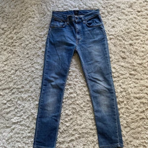 Tiger of Sweden Jeans - Ett par blåa jeans från märket tiger of Sweden. Storleken i waist är 29 och i length är den 32. Det är mycket bra skick på jeansen som är köpta begagnade nu i sommar och i mycket bra skick. Dom är stilrena, snygga och passar bra till dig som letar efter ett par nya jeans. Hör av dig vid minsta fundering och tveka inte på att fråga.