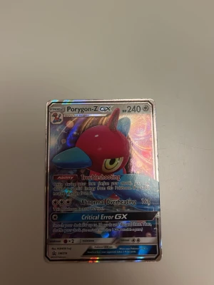 Porygon-Z GX Pokémonkort holografiskt - Säljer ett holografiskt Porygon-Z GX Pokémonkort med 240 HP. Kortet har färger i rött, blått och gult och glänsande yta. Text och illustration är tydliga och kortet är på engelska. Perfekt för samlare eller Pokémonfans.