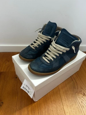 Blå Maison Margiela High tops  - Blå maison margielas i storlek 40, är stora i storleken så passar även 41. Originalkartong och dustbags tillkommer. De är i använt skick men har inga större deffekter, nypris 6999kr. Hör av er vid frågor. 